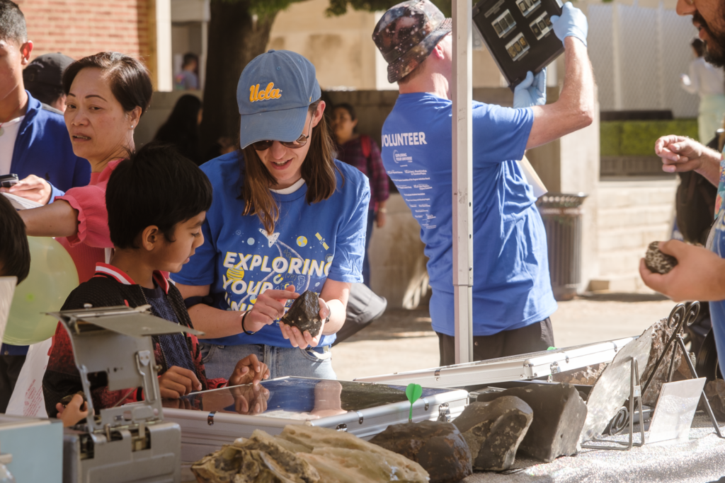UCLA EPSS volunteer demonstrates structures in a meteorite to a child attending EYU 2022.