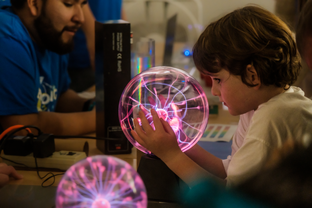 Child discovers the wonders of plasma through a Tesla Ball at the EPSS Space Weather booth at EYU 2022.